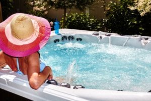 A lady wearing a hat and a swimsuit relaxing in a hot tub