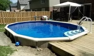An above ground pool, built in backyard of a house adjacent to the deck of the house, from Splashworks Pool and Spa